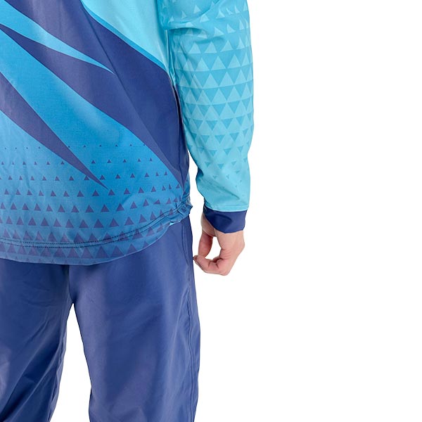 dos d'une personne portant une veste turquoise sublimée et un pantalon bleu