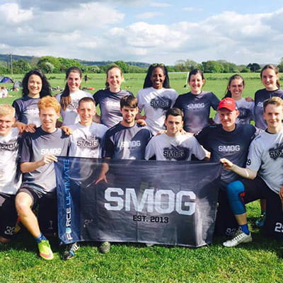 team posing on grass field with smoky jerseys and black smog flag