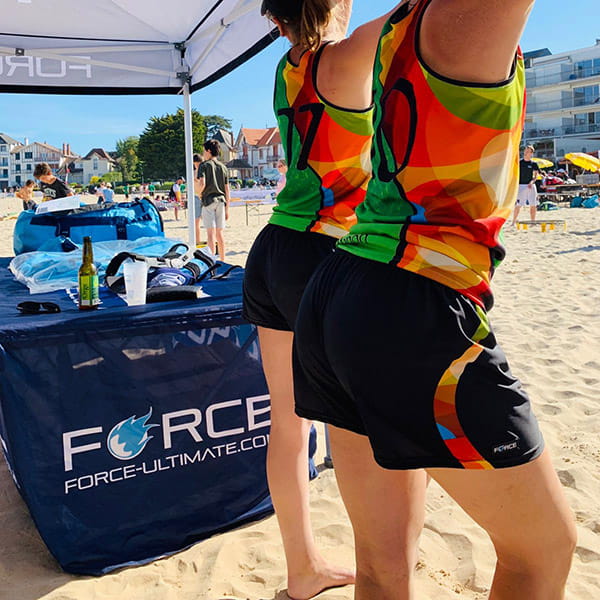 femmes de profil sur la plage sous une tente portant des maillots colorés et des shorts noirs courts